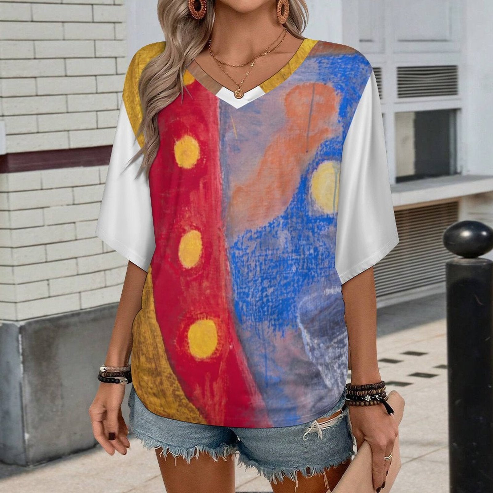 Person wearing a colorful abstract-patterned shirt with denim shorts in an urban setting.